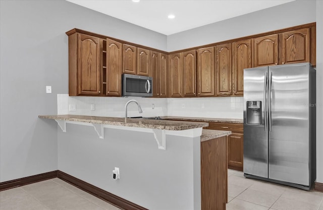 kitchen featuring light tile patterned floors, a breakfast bar, backsplash, stainless steel appliances, and kitchen peninsula