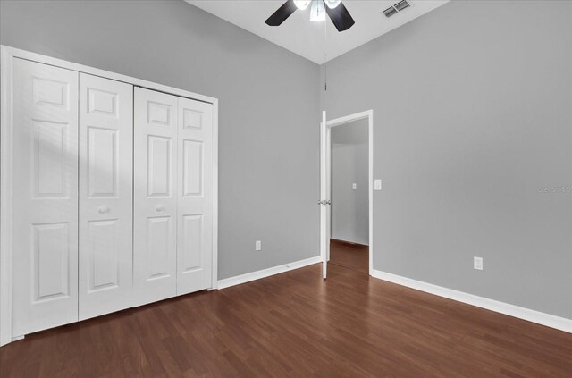 unfurnished bedroom featuring dark wood-type flooring, a closet, and ceiling fan