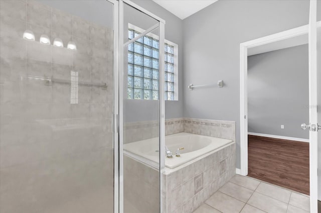 bathroom featuring a relaxing tiled tub and tile patterned flooring