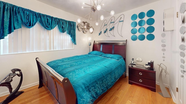 bedroom featuring an inviting chandelier and light hardwood / wood-style flooring