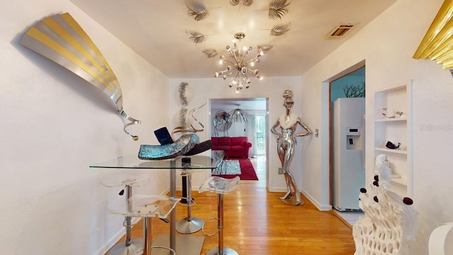 hall featuring hardwood / wood-style flooring, built in features, and a chandelier