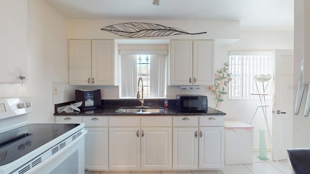 kitchen with tasteful backsplash, sink, white cabinets, and electric stove