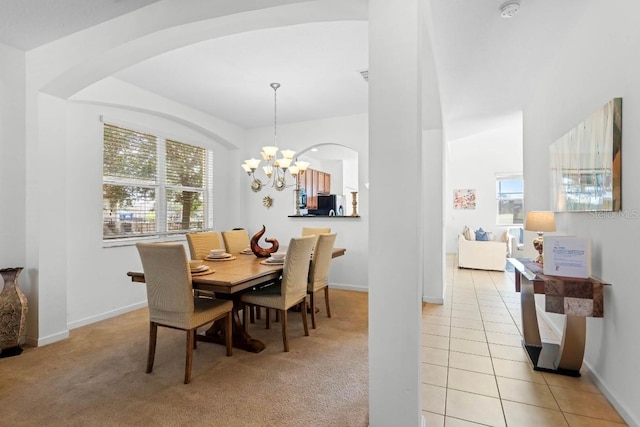 carpeted dining space with an inviting chandelier and a healthy amount of sunlight