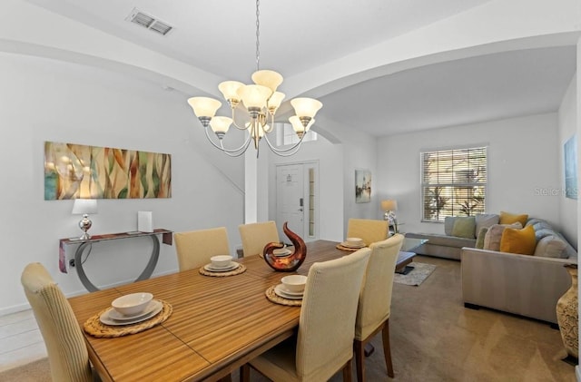 carpeted dining space with an inviting chandelier