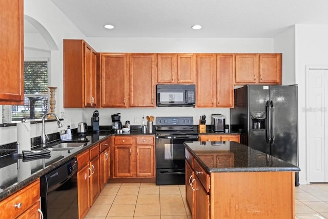 kitchen featuring a kitchen island, black appliances, sink, light tile patterned floors, and dark stone counters