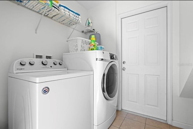 clothes washing area featuring washer and dryer and light tile patterned floors