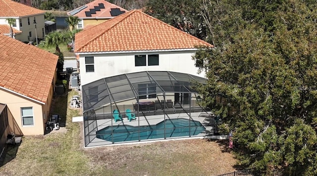 back of house with a lanai, a lawn, and a patio area