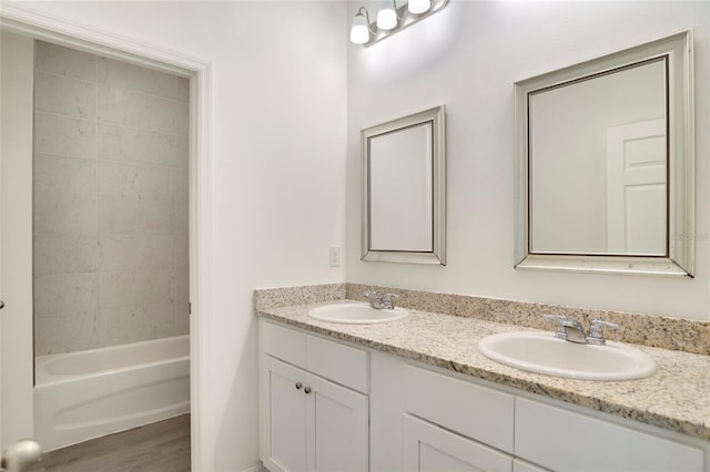 bathroom with hardwood / wood-style flooring, tiled shower / bath, and vanity