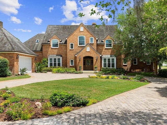 view of front of home featuring brick siding, decorative driveway, an attached garage, and a front lawn