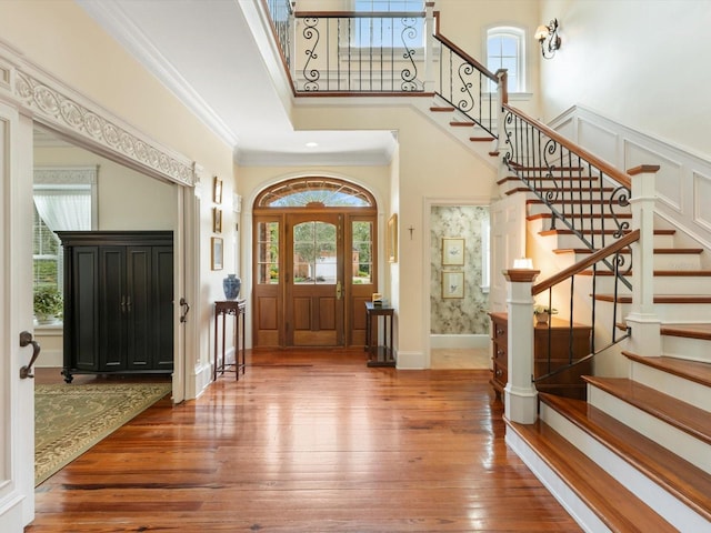 foyer featuring hardwood / wood-style flooring, a high ceiling, ornamental molding, baseboards, and stairs