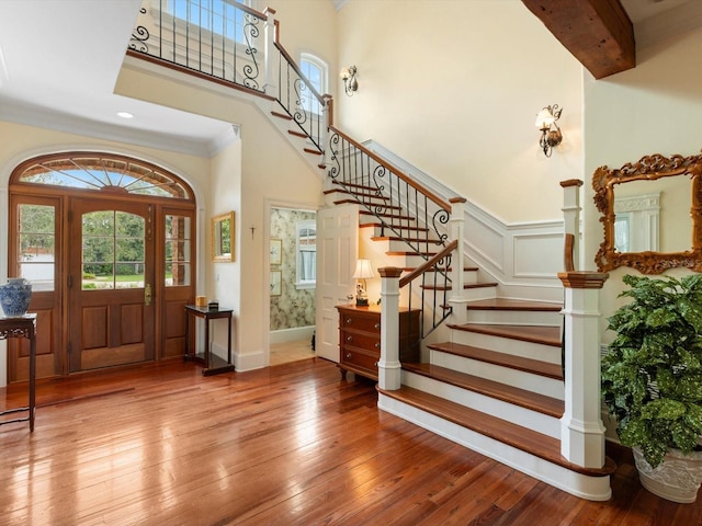 entryway featuring a high ceiling, stairway, plenty of natural light, and hardwood / wood-style flooring