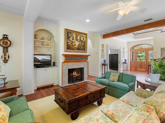 living room with visible vents, ornamental molding, ceiling fan, wood finished floors, and a lit fireplace