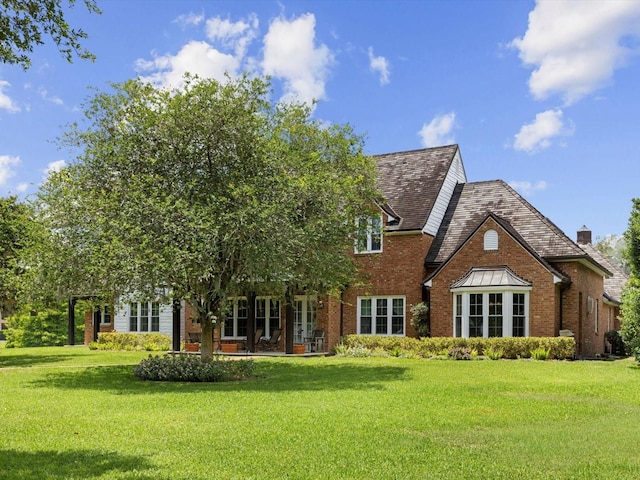 rear view of house featuring a yard and brick siding