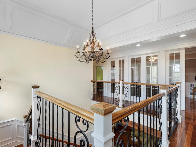 stairway featuring crown molding, wainscoting, a decorative wall, and wood finished floors