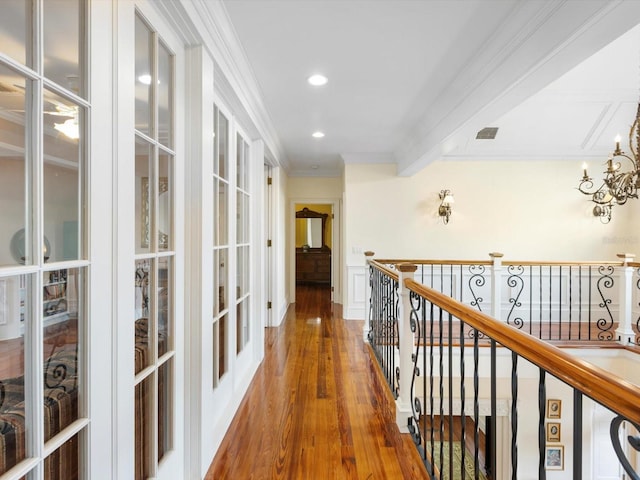 hall with a chandelier, wood finished floors, visible vents, an upstairs landing, and crown molding