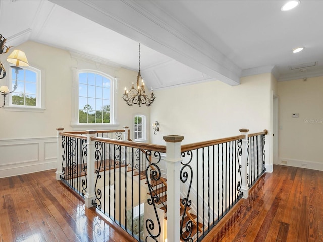 hall with an upstairs landing, ornamental molding, a decorative wall, and hardwood / wood-style floors