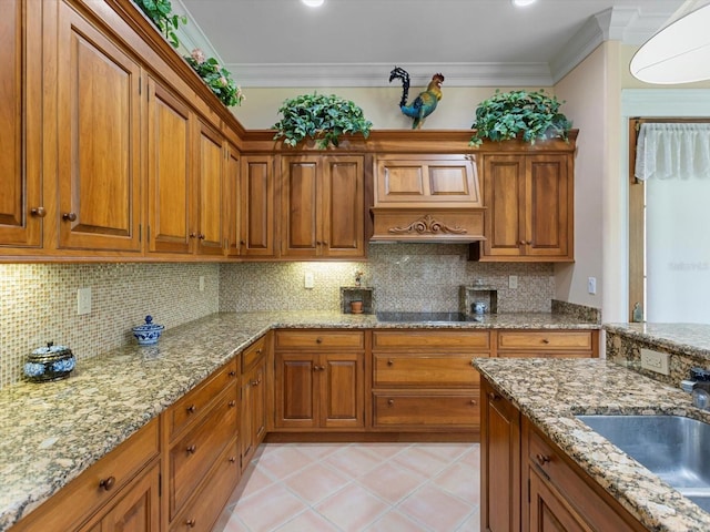 kitchen featuring brown cabinetry, crown molding, decorative backsplash, and a sink