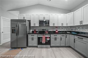 kitchen with white cabinetry, vaulted ceiling, light hardwood / wood-style flooring, gray cabinets, and stainless steel appliances