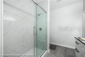 bathroom featuring a shower with door, vanity, and hardwood / wood-style flooring