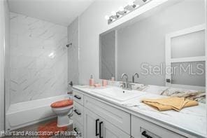 full bathroom featuring vanity, tiled shower / bath combo, and toilet