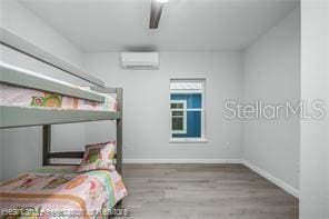 bedroom featuring hardwood / wood-style floors and a wall mounted AC