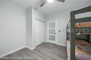 unfurnished bedroom with ceiling fan, wood-type flooring, and a closet