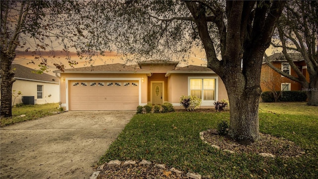 view of front of house featuring a garage, a yard, and central AC unit