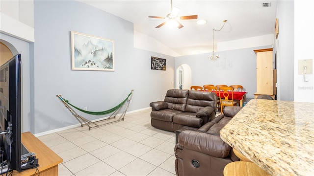 tiled living room featuring lofted ceiling and ceiling fan with notable chandelier