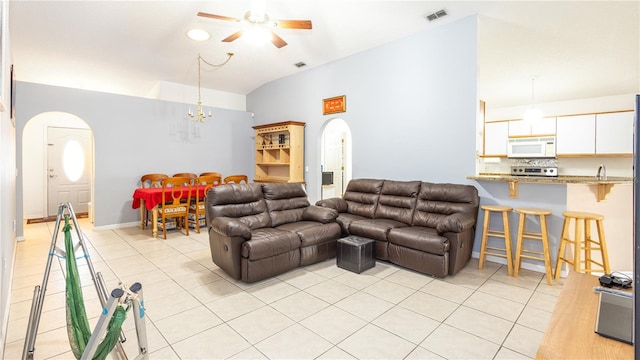 living room with lofted ceiling, ceiling fan with notable chandelier, and light tile patterned floors