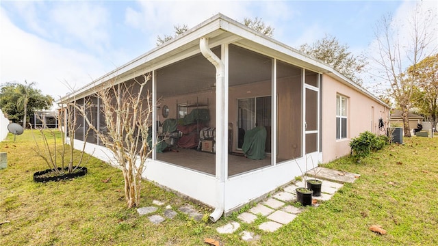 view of home's exterior featuring central AC unit, a yard, and a sunroom