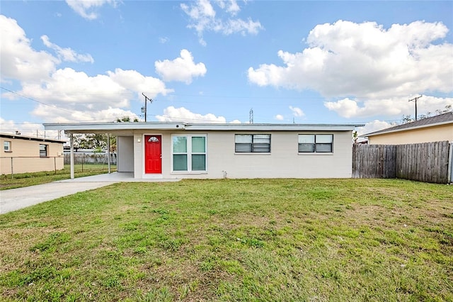 view of front facade with concrete driveway, a carport, a front yard, and fence