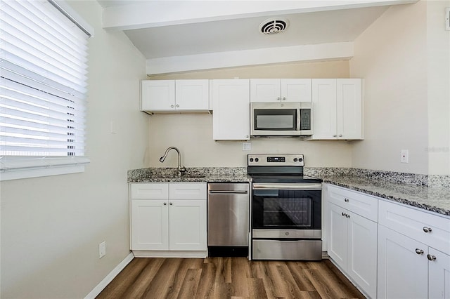 kitchen featuring lofted ceiling with beams, stainless steel appliances, a sink, and visible vents