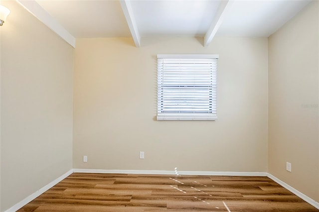 unfurnished room with beamed ceiling, wood finished floors, and baseboards