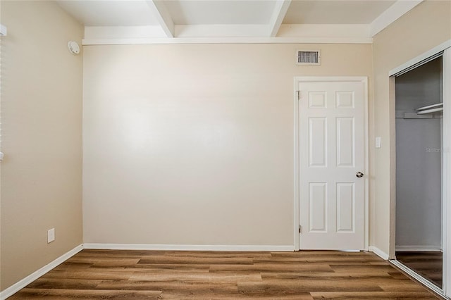 interior space with beam ceiling, visible vents, baseboards, and wood finished floors