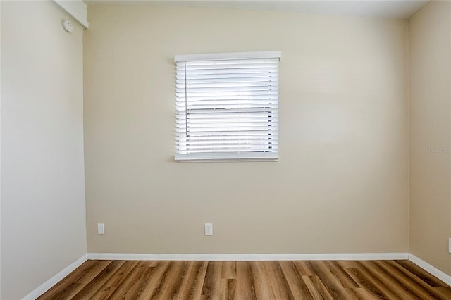 spare room with baseboards and wood finished floors