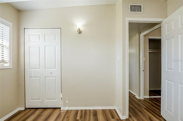 hall featuring baseboards, visible vents, and wood finished floors