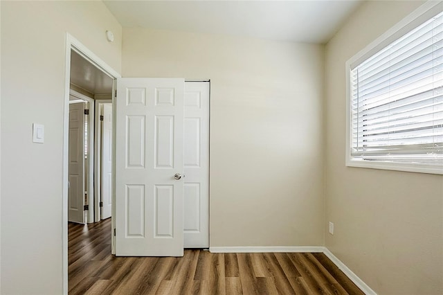 unfurnished bedroom featuring a closet, wood finished floors, and baseboards