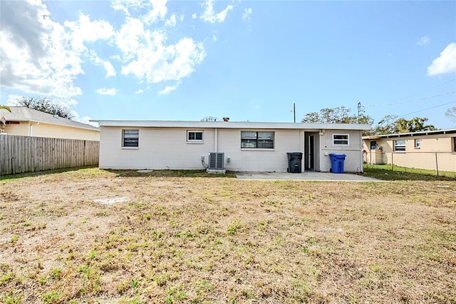 rear view of house featuring a patio area, a fenced backyard, a lawn, and central AC