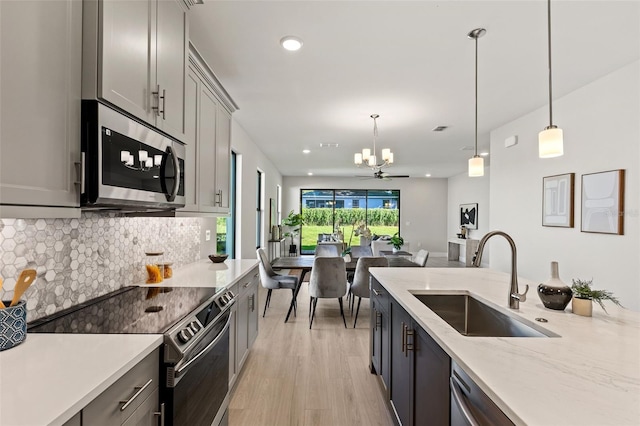 kitchen with stainless steel appliances, pendant lighting, sink, and gray cabinetry