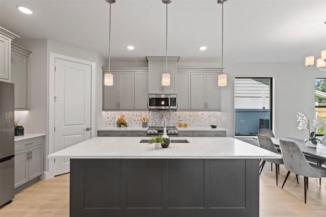 kitchen with gray cabinetry, decorative light fixtures, and stainless steel appliances