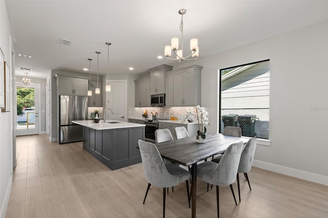 dining area featuring sink, an inviting chandelier, and light hardwood / wood-style flooring