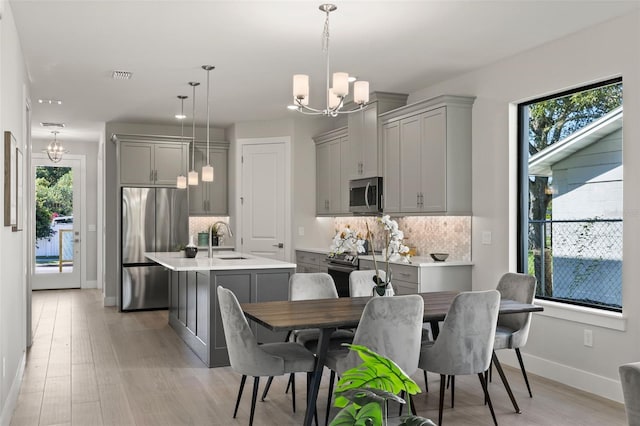 dining area with sink, a wealth of natural light, a chandelier, and light wood-type flooring