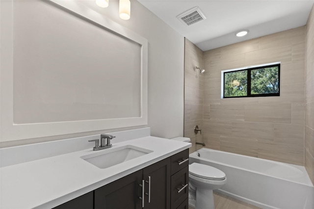 full bathroom featuring tiled shower / bath, vanity, and toilet