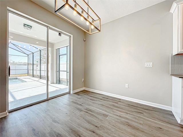 unfurnished dining area featuring wood-type flooring and a textured ceiling