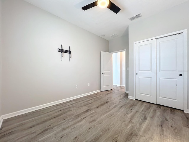 unfurnished bedroom featuring ceiling fan, light wood-type flooring, and a closet