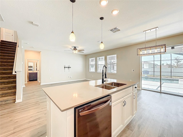 kitchen with sink, dishwasher, white cabinetry, a healthy amount of sunlight, and a center island with sink