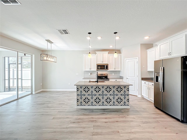 kitchen with stainless steel appliances, white cabinetry, and pendant lighting