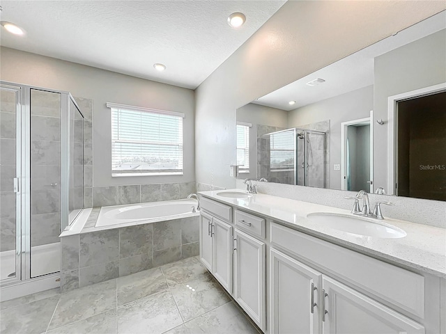 bathroom with independent shower and bath, vanity, and a textured ceiling