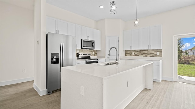 kitchen with white cabinetry, sink, hanging light fixtures, a kitchen island with sink, and stainless steel appliances