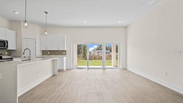 kitchen featuring white cabinetry, sink, backsplash, and hanging light fixtures